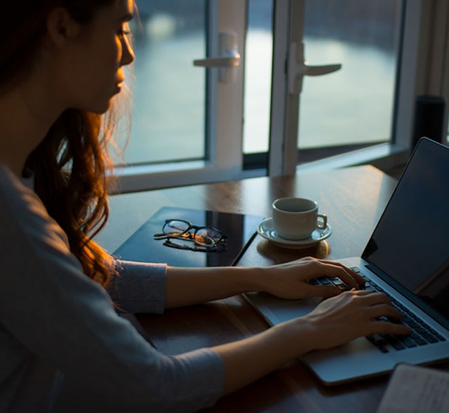 Woman seated at a desk typing on a laptop