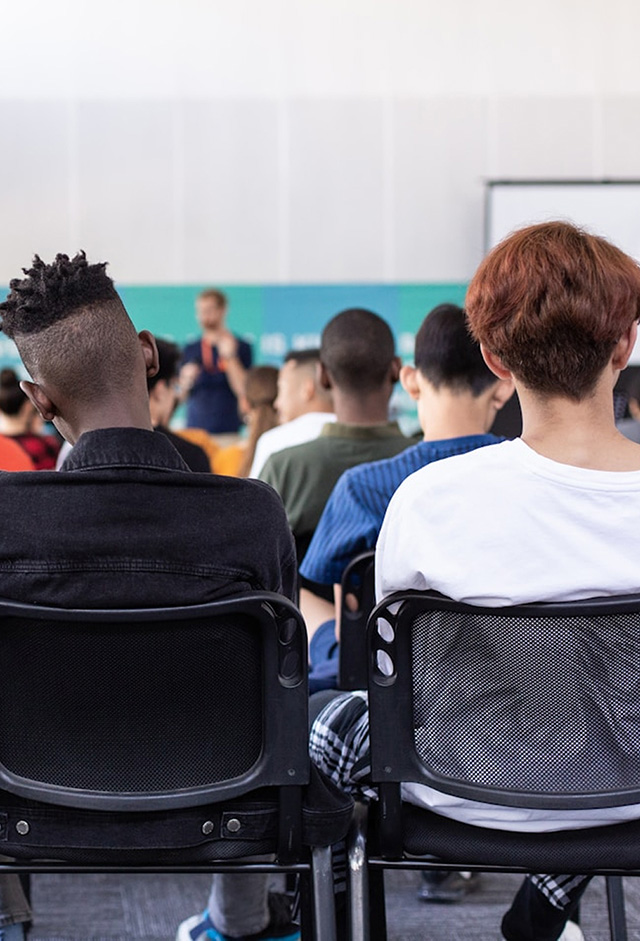 Students seated in chairs in a classroom, seen from behind