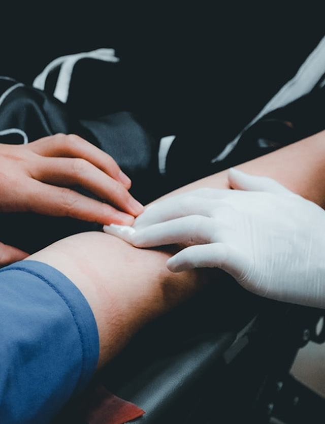 Gloved hands applying pressure to a person's outstretched arm