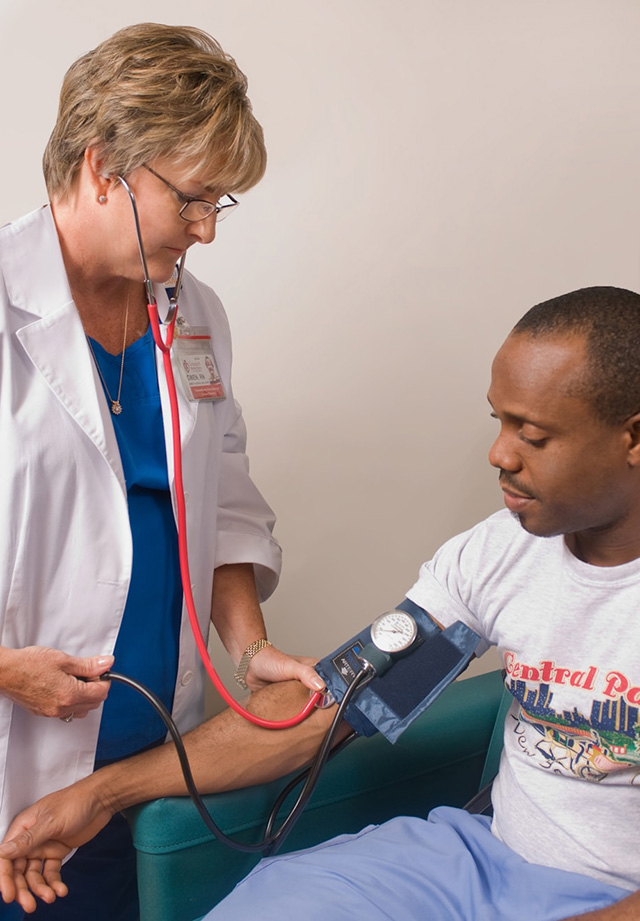 Woman in medical scrubs measuring a patient's blood pressure