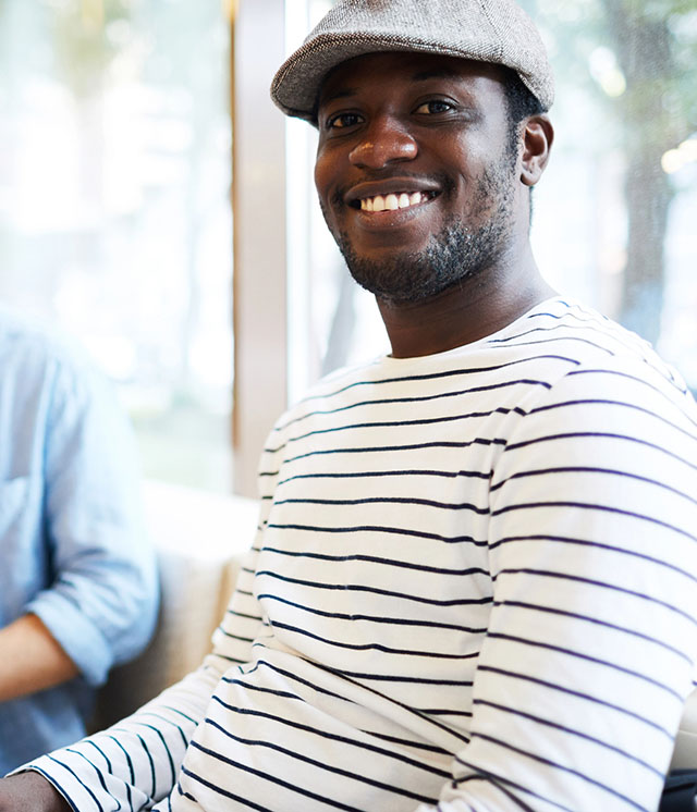 Man in a gray cap and striped shirt smiling at the camera