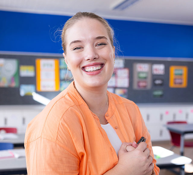 Woman in a classroom, smiling at the camera