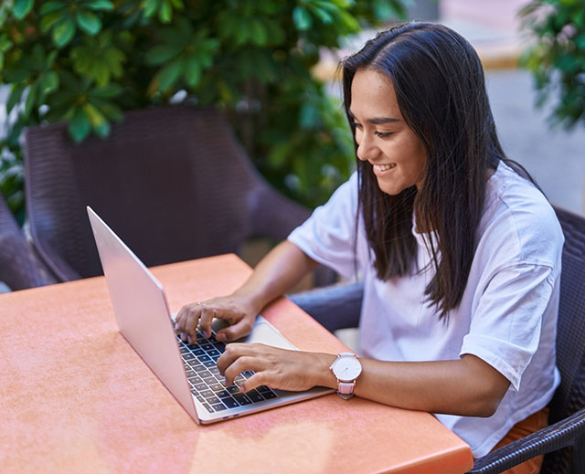 Woman sitting at a table typing on a laptop