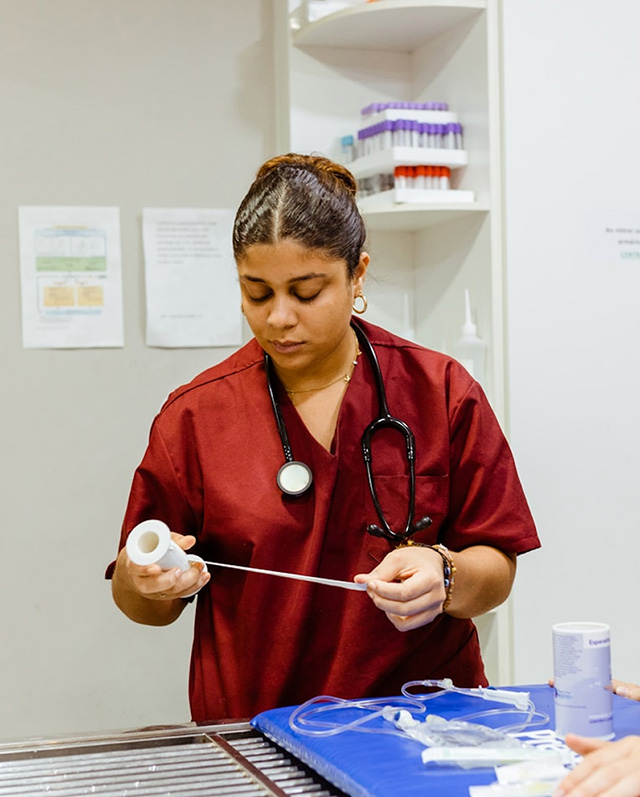Woman in red medical scrubs measuring a piece of medical tape