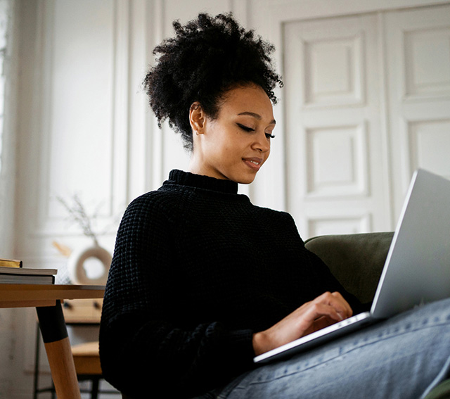 Seated woman typing on a laptop in her lap