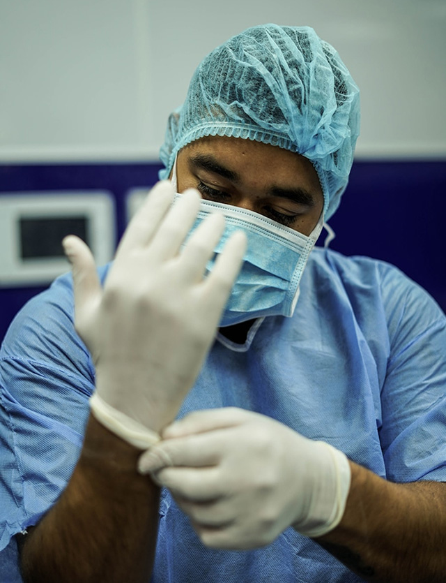 Person in medical scrubs putting on gloves