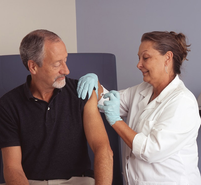 Older man receiving an injection from a medical professional
