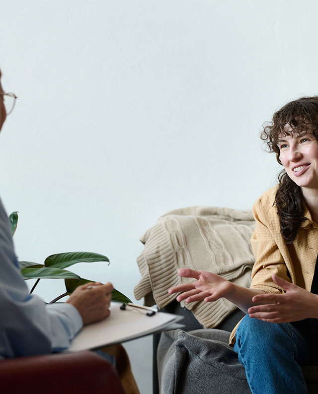 Seated woman interacting with a person taking notes