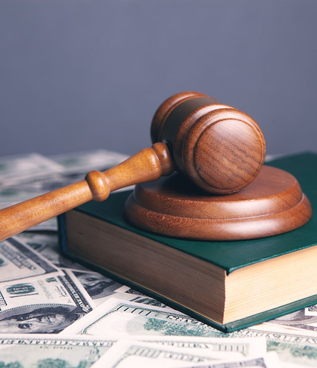 Gavel resting on a book, resting on a table covered in American currency