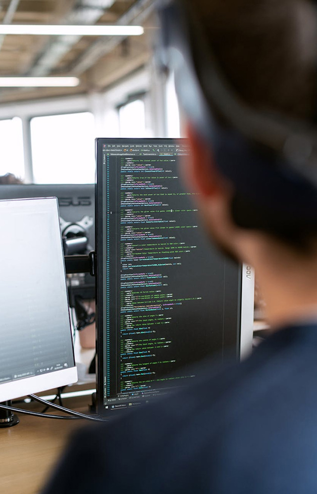 Computer monitor displaying code, seen from over a person's shoulder
