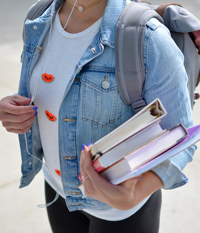 Close-up of a woman wearing a backpack, holding school books