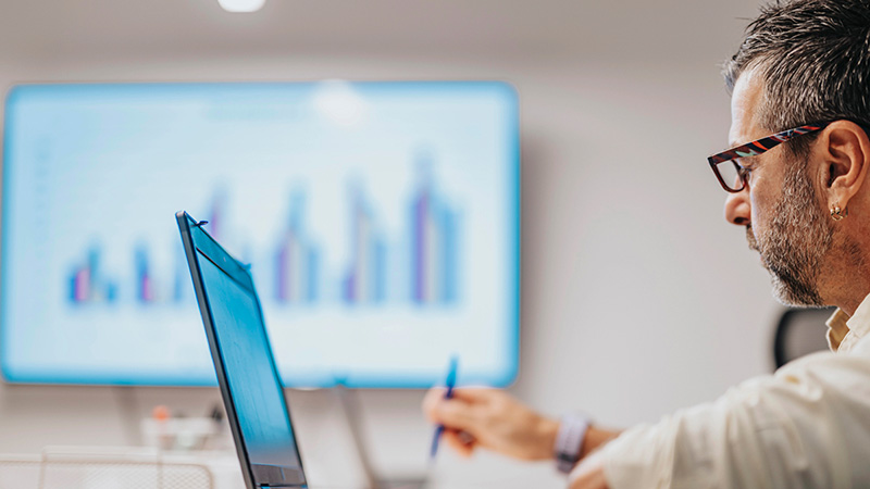 Man seated at a table, working on a laptop.