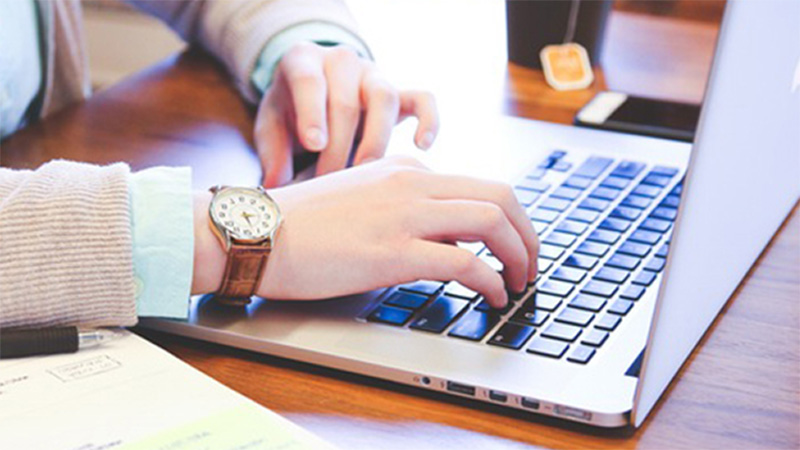 Hands typing on a laptop