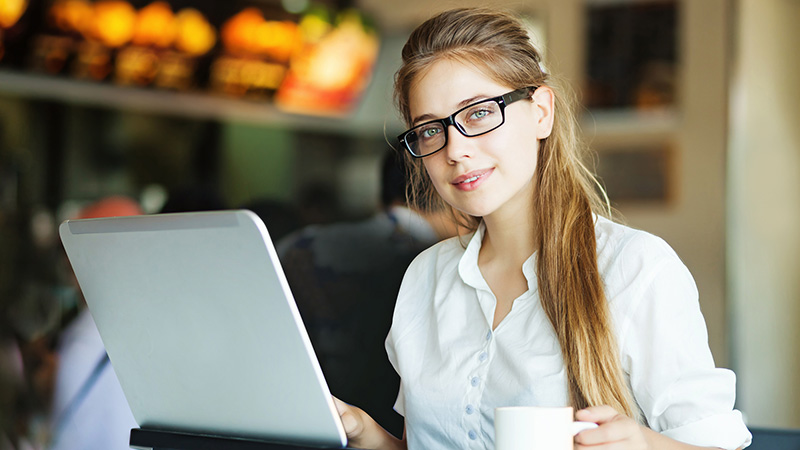 Woman working at a laptop, smiling at the camera