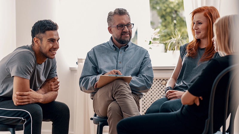 Group of four people seated in a semi-circle engaging in a dicussion