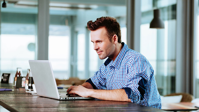 Man seated at a table, using a laptop
