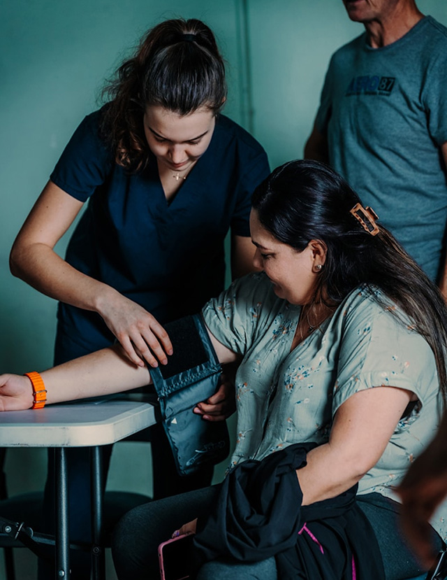 Person putting blood pressure cuff on a patient