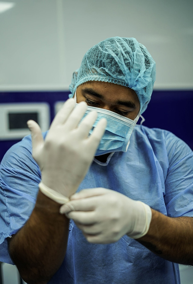 Person in medical scrubs putting on rubber gloves